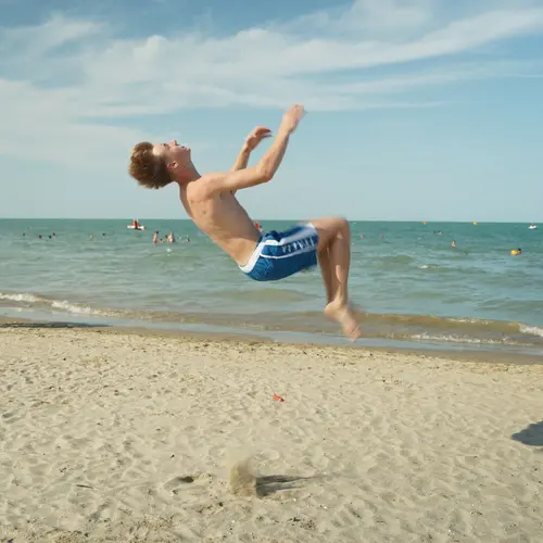 Ein Junge macht einen Salto am Strand von Rimini.