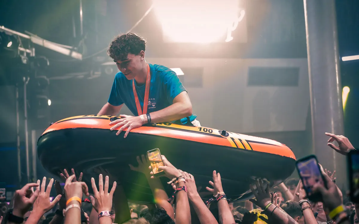 Ein junger Mann im blauen Team-Shirt lässt sich beim Crowdsurfen in einem Schlauchboot im Club feiern auf einer FUN-Jugendreise 2026.