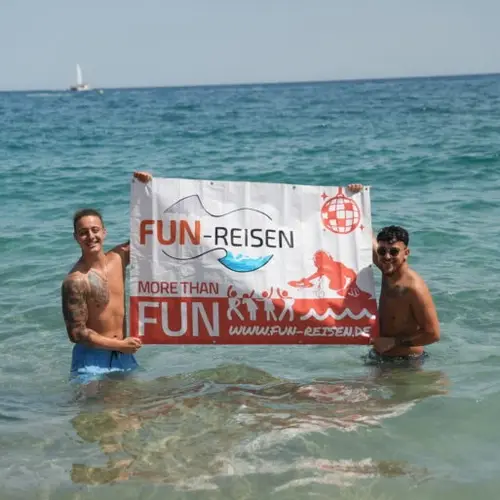 Zwei Jugendliche halten ein FUN-Jugrendreisenbanner im Wasser hoch.