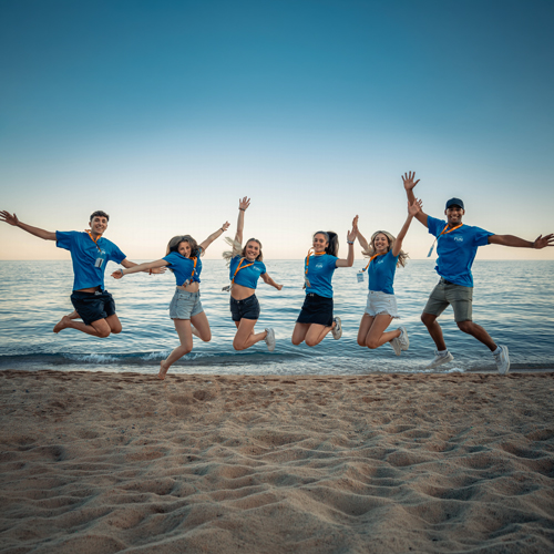 Junge Menschen springen in Spanien vor Freude am Strand in die Luft