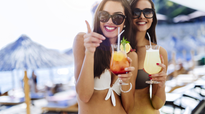 Girls drinking cocktails on beach  - © NDABCREATIVITY - stock.adobe.com