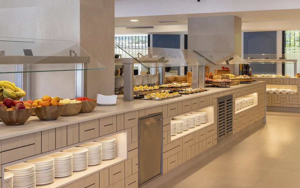 Langes, reichhaltiges Buffet mit Früchten, Gebäck und warmen Speisen in einem modernen Restaurant