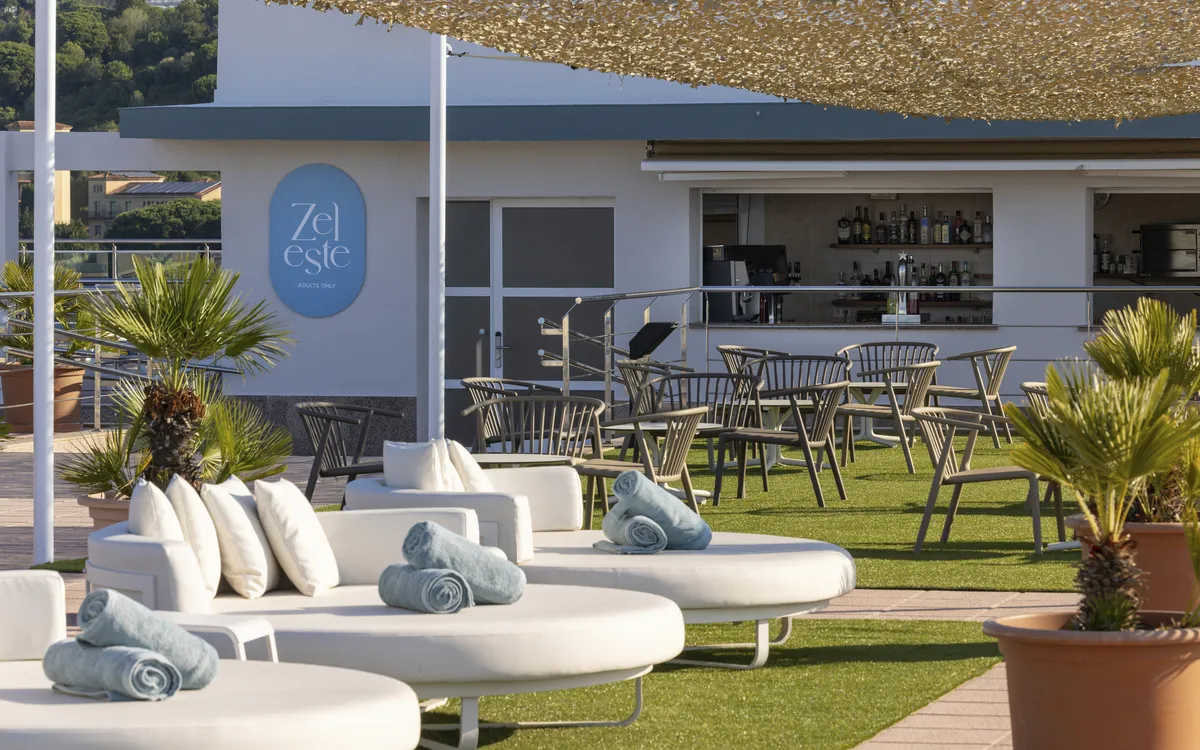 Dachterrasse mit Lounge-Möbeln, Bar, Kunstrasen und blauen Handtüchern