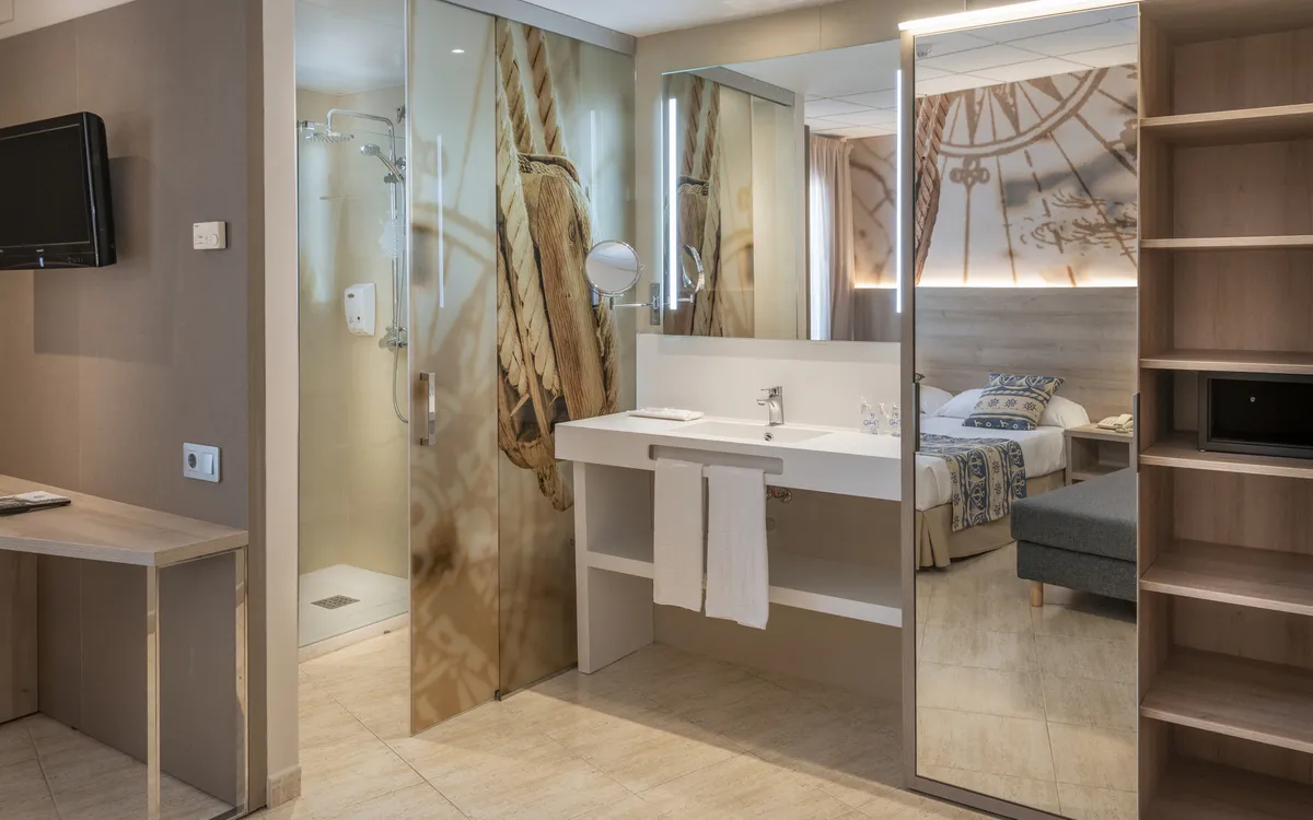 Ein renoviertes, helles Badezimmer mit einer begehbaren Dusche, großem Spiegel und Föhn.