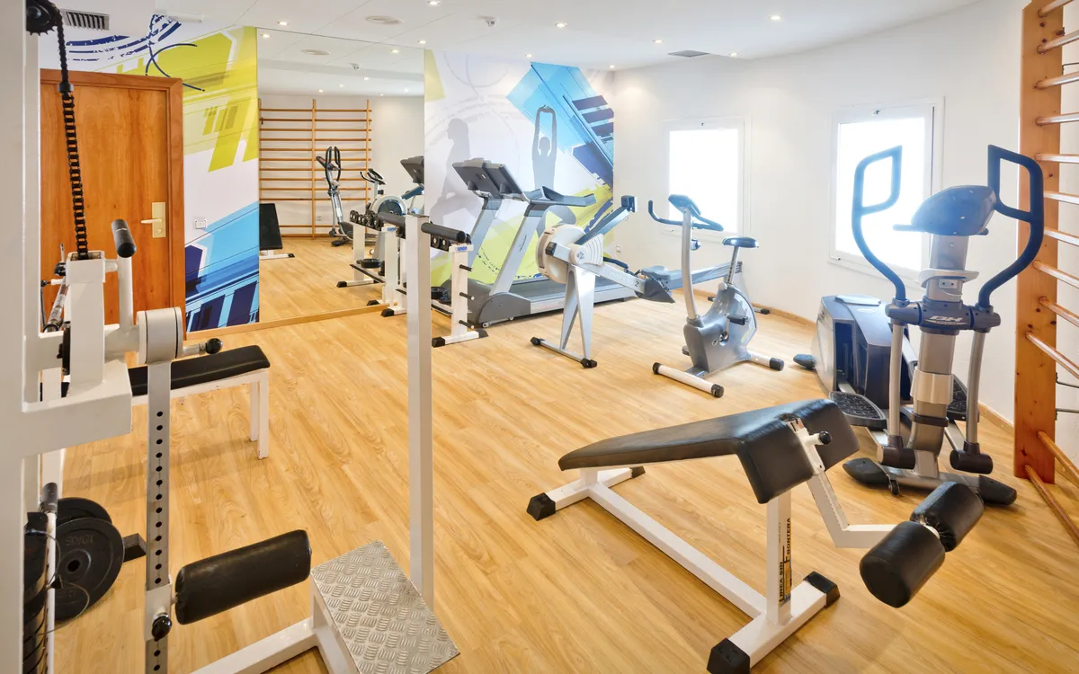 Ein heller Fitnessraum mit Kardiogeräten und Kraftstationen für das tägliche Workout im Urlaub.