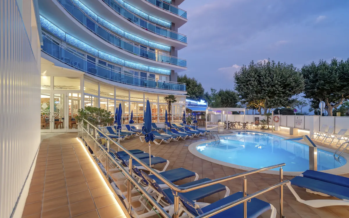 Ein blauer Swimmingpool im ruhigen Innenhof des Hotels, umgeben von Sonnenliegen und Palmen.