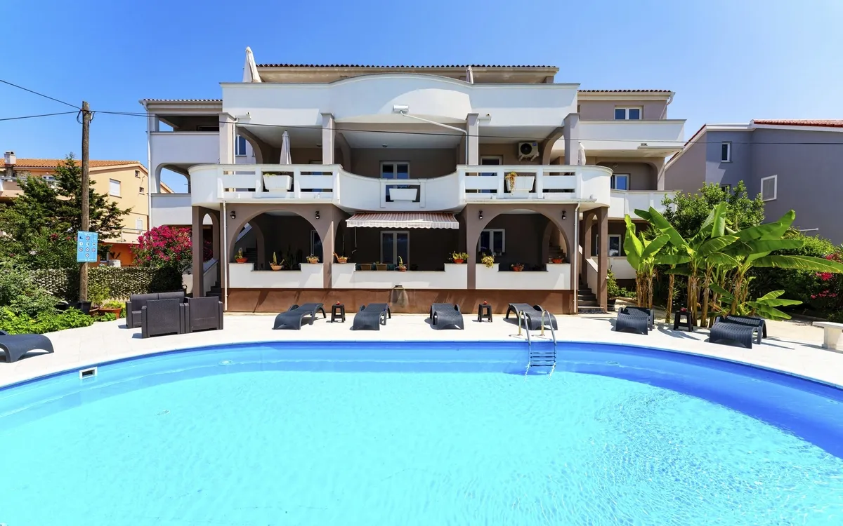 Großer Gemeinschaftspool mit Liegen und Sonnenschirmen bei den Premium Appartements