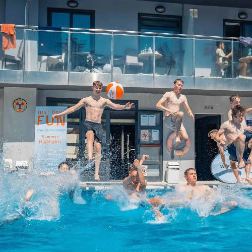 Junge Leute springen in den Pool und haben Offensichtlich Spaß auf ihrer Jugendreise